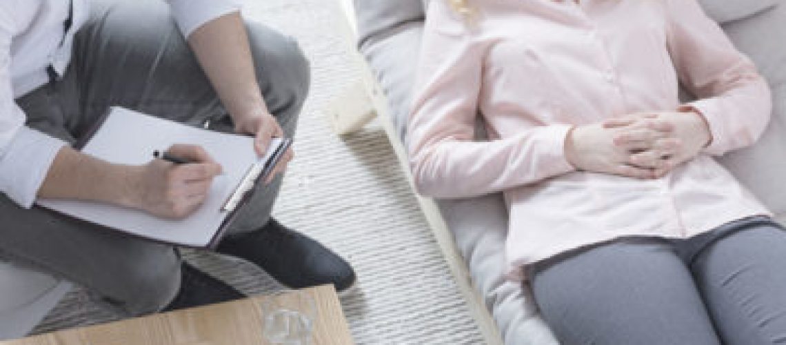 Woman in hypnosis lying on psychotherapist sofa